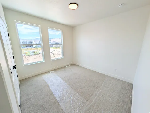 Bright room featuring two large windows, neutral wall paint, and light-colored carpeting