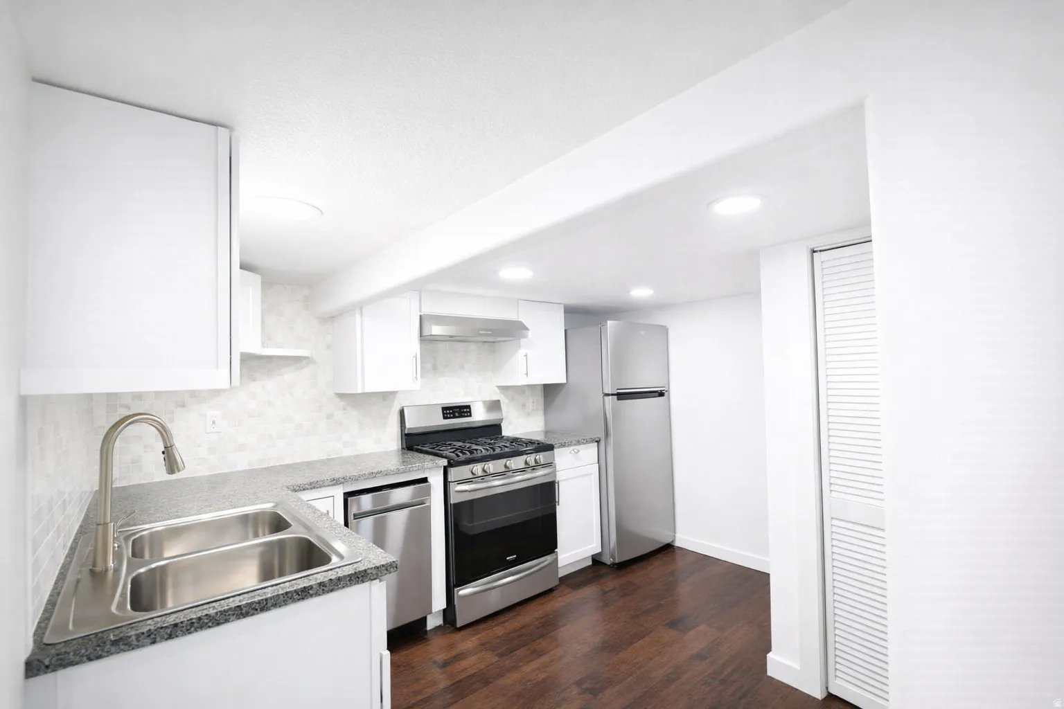 Full second kitchen in basement with all stainless appliances including gas range, range hood, double sink, stainless refrigerator and dishwasher.