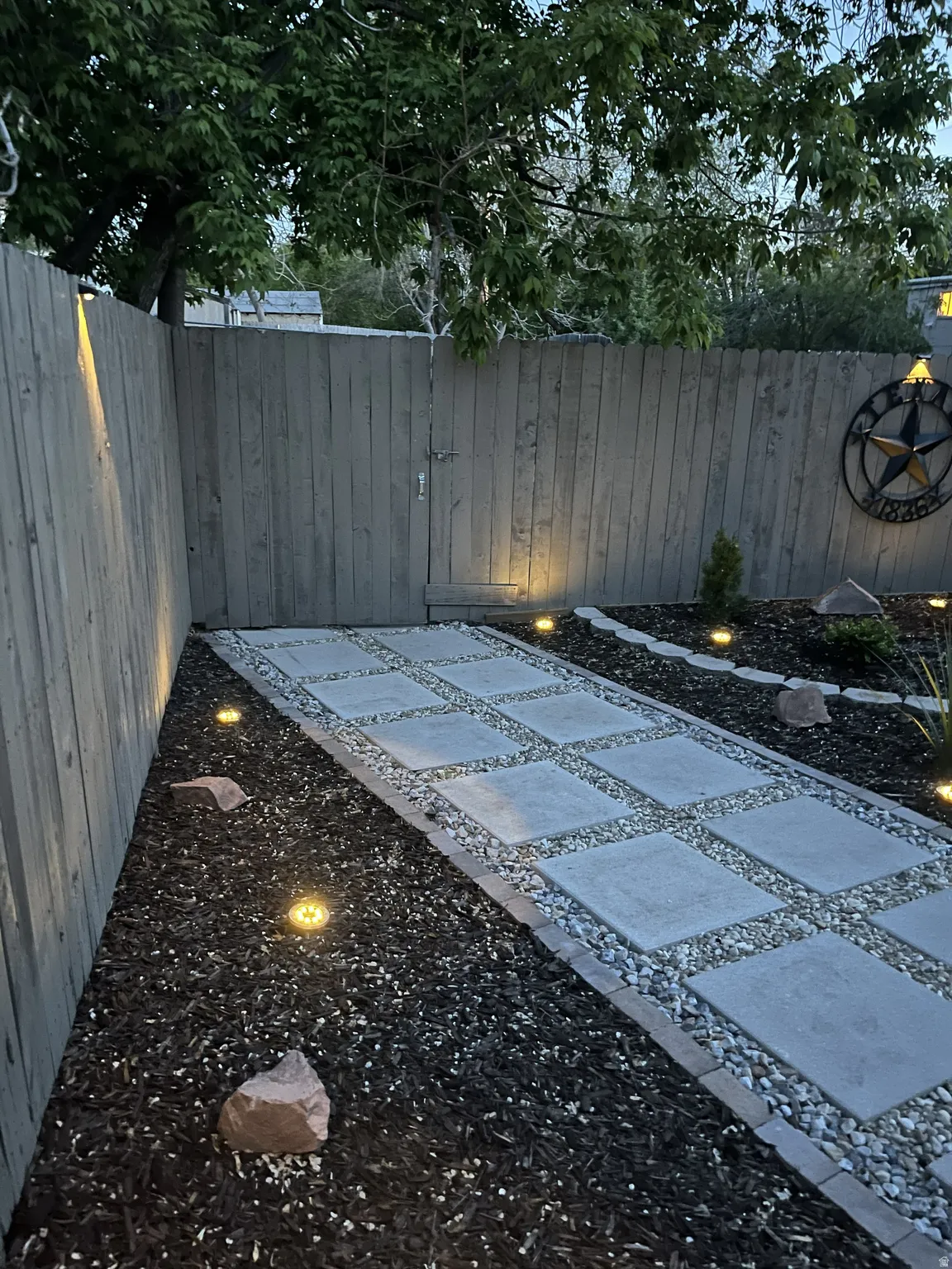 Xeriscaped backyard with pavers and accent lighting.