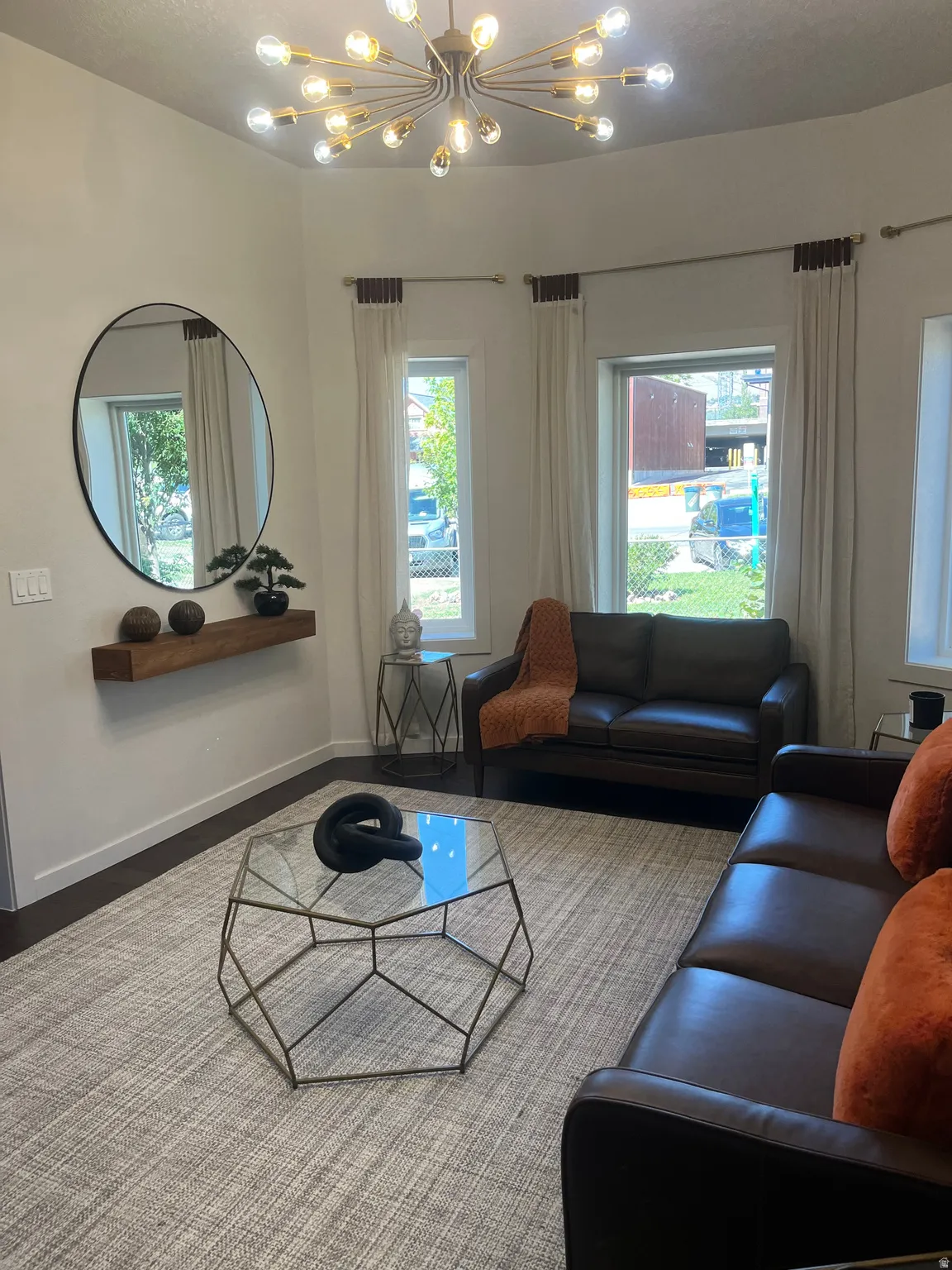 High ceilings featuring a Sputnik-style chandelier, dark wood flooring, and a floating shelf