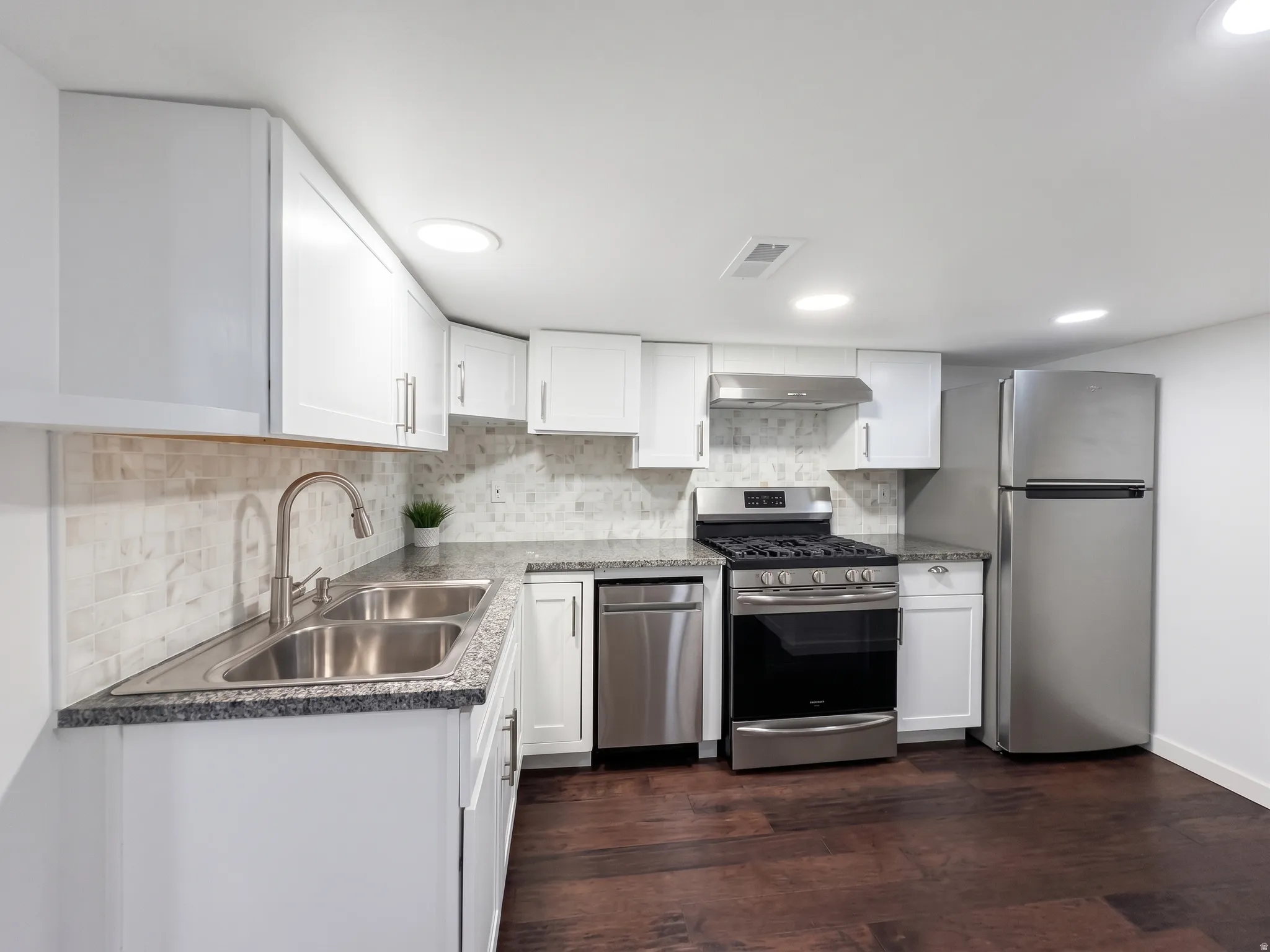Second kitchen is enhanced with brushed nickel hardware, granite countertops, stainless steel appliances, tile backsplash, and wood flooring