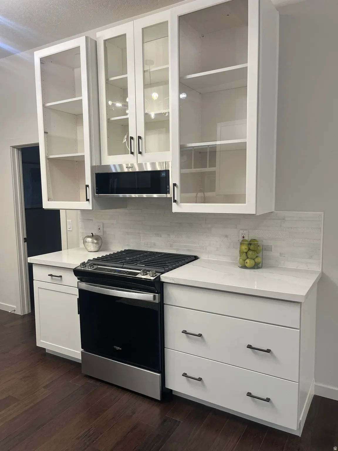 Glass-front upper cabinets, stainless steel gas range, and a built-in microwave