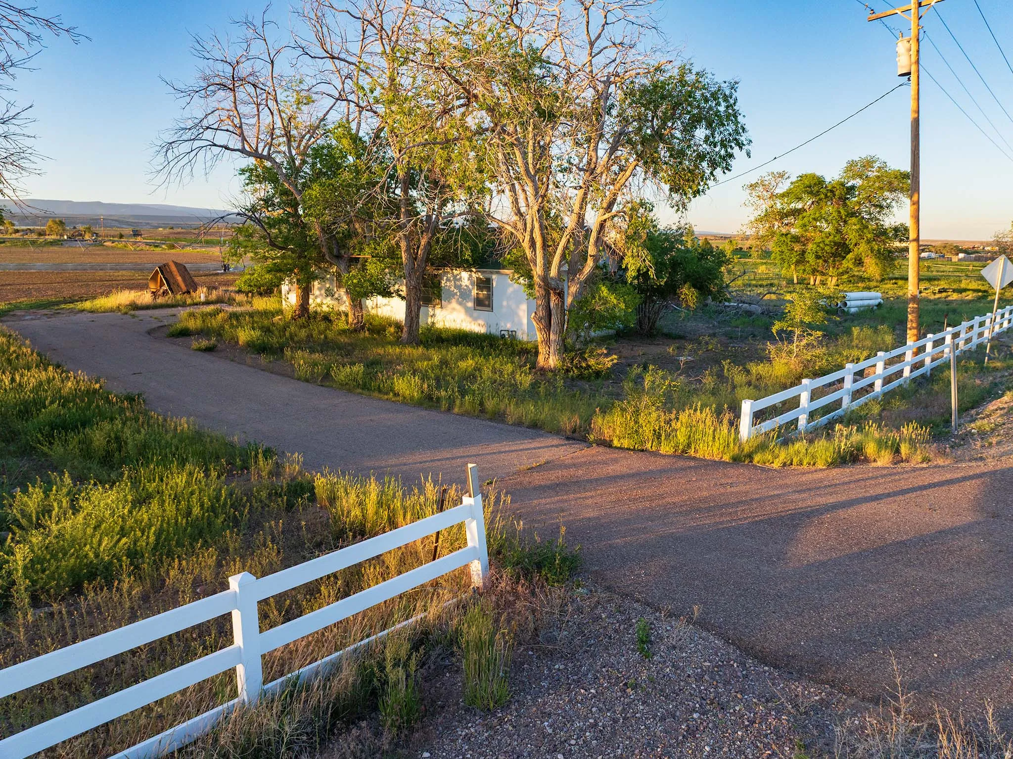 Paved driveway with white fence bordering the property