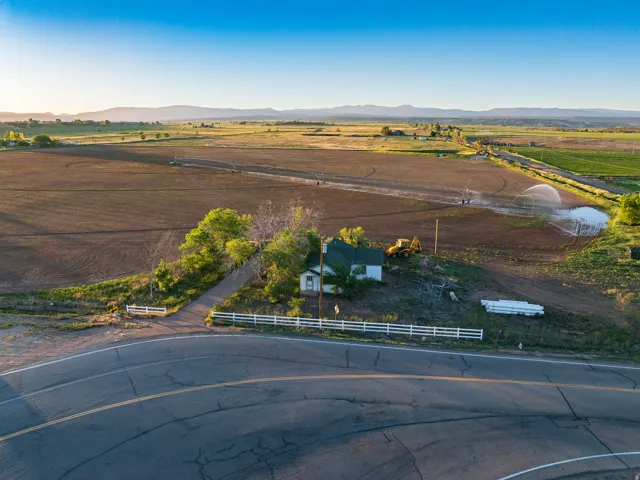 Expansive agricultural land featuring a single-family residence, mature trees, and a white picket fence