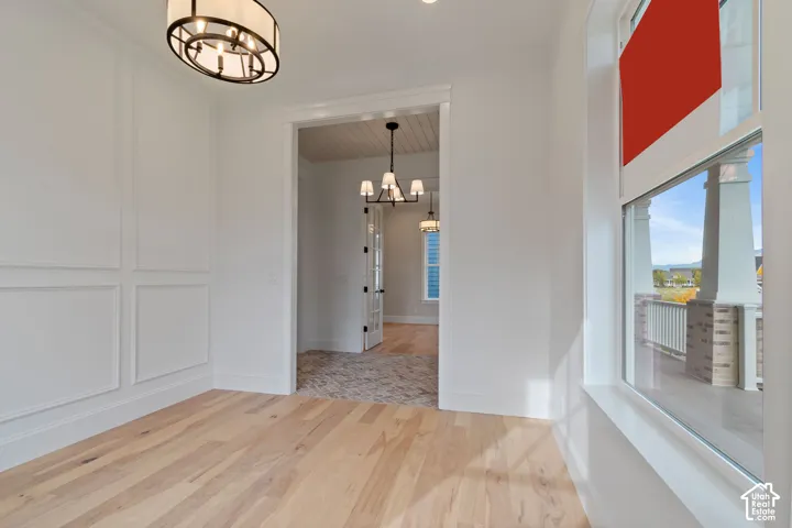 Hardwood flooring, decorative wall paneling, and an overhead light fixture
