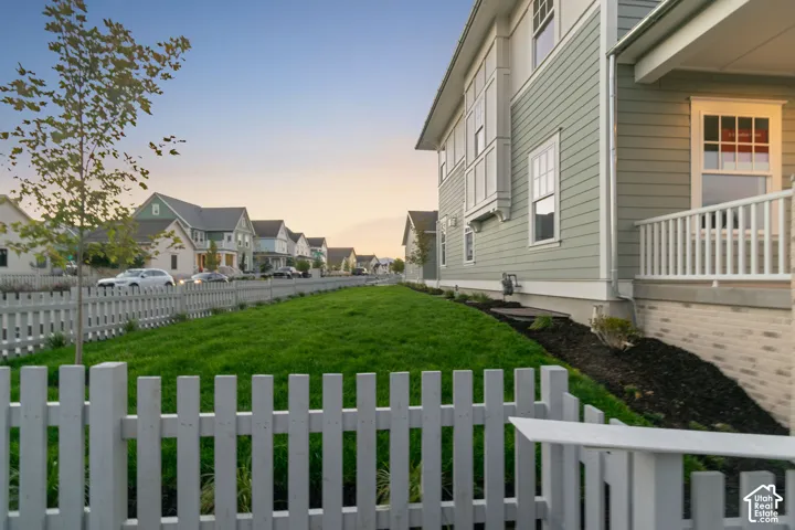 Street-facing exterior with a white picket fence, a manicured lawn, and a light green siding facade
