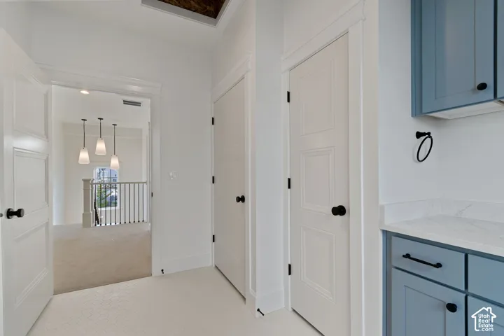 Hallway featuring white paneled doors with matte black hardware, mosaic tile flooring, and custom blue cabinetry with a light-toned countertop