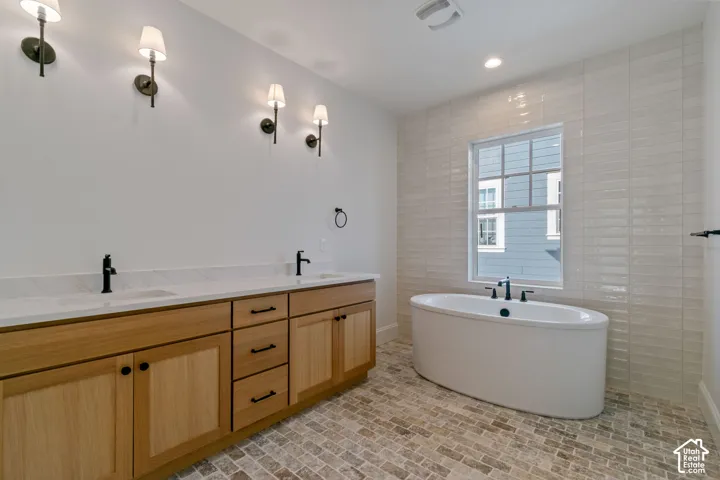 Dual vanity with light wood-finish cabinetry, white countertops, and matte black fixtures