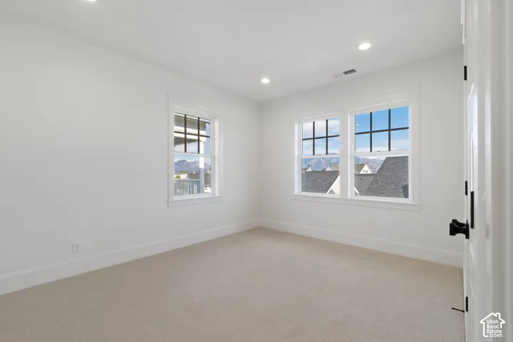 Light-filled room with two large windows, recessed lighting, and soft carpeting