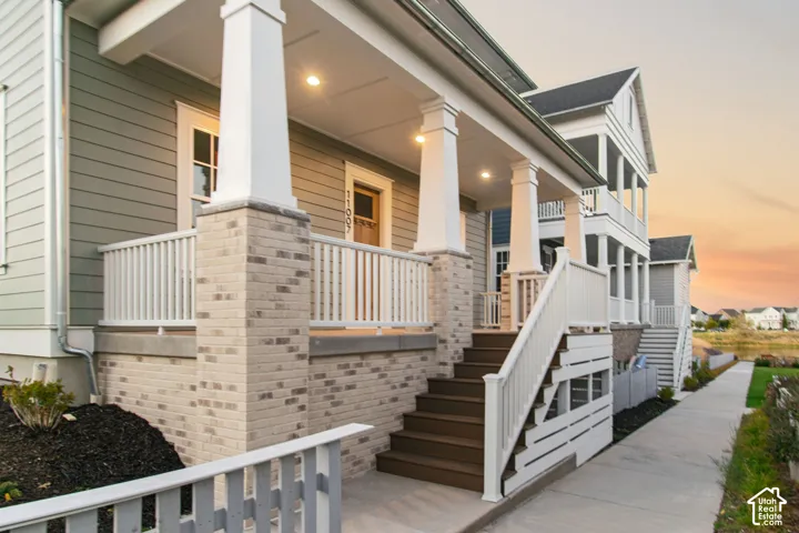 Porch with white railings, brown composite steps, light gray brick base, and recessed lighting