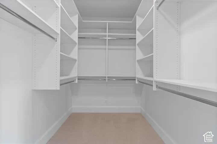 White custom closet system with adjustable shelving, multiple hanging rods, and carpeting