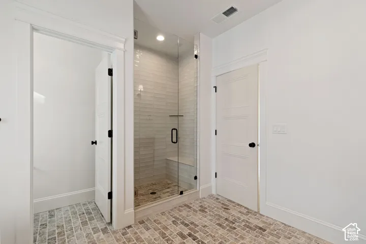 Walk-in shower with clear glass enclosure, tiled walls, and a built-in bench