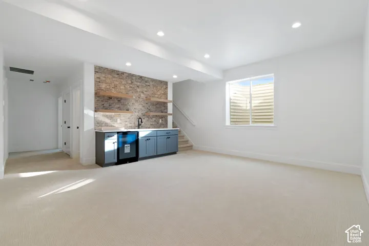 Built-in wet bar with a beverage refrigerator, brick accent wall, floating wood shelves, and recessed lighting
