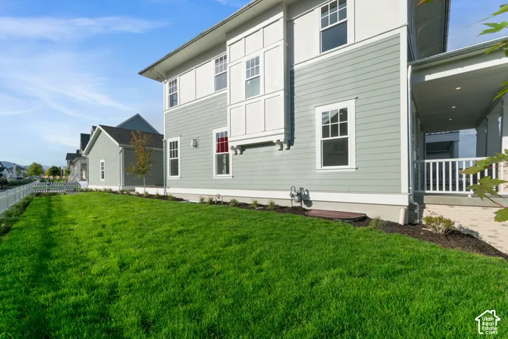 Expansive green lawn, light-toned siding, white trim, white window frames, and covered porch with white railings