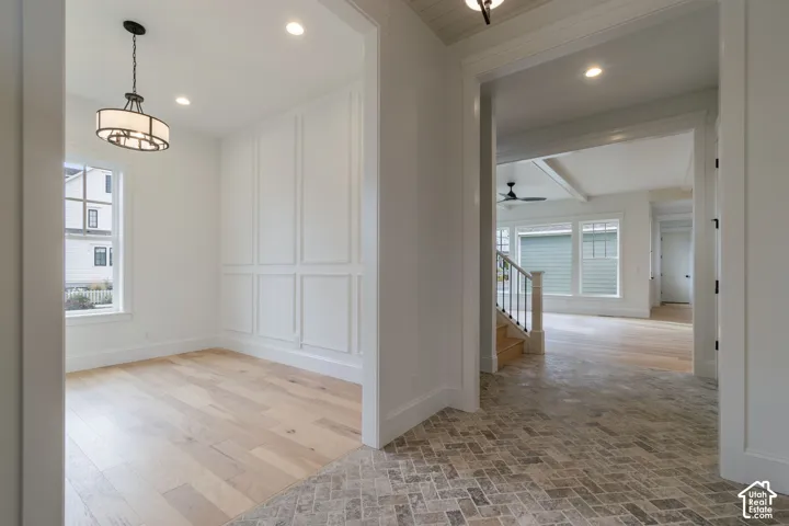 Herringbone-patterned tile flooring, wood-finish flooring, wainscoting with decorative trim, recessed lighting, and a contemporary chandelier