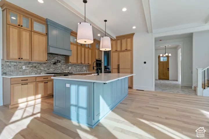 Gourmet kitchen with light wood-finish cabinetry, a blue island with a white countertop, and a tiled backsplash