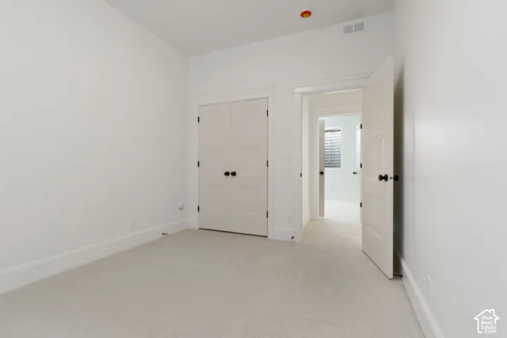 Neutral carpet flooring, white walls, white trim, white paneled doors, and matte black hardware
