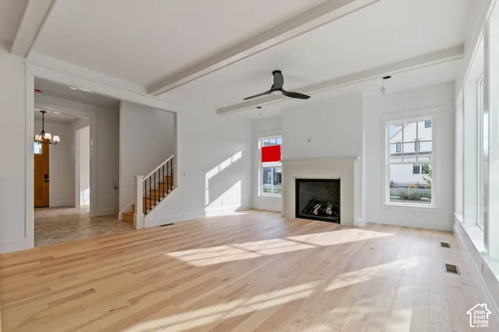 Wood-finish flooring, white walls, and a fireplace with a white mantel are featured