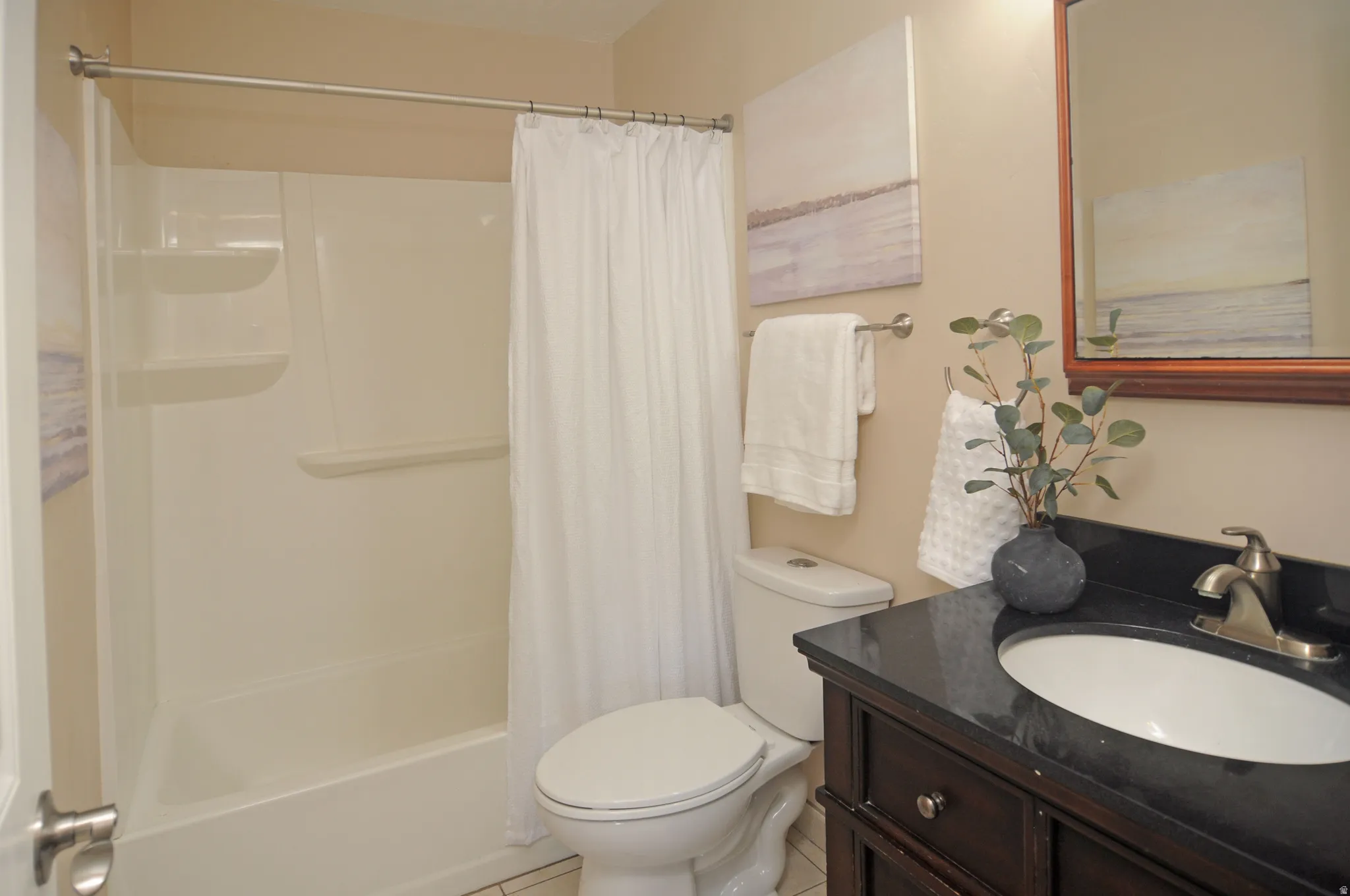 Bathroom featuring a dark wood-finish vanity, undermount sink, dark countertop, and brushed nickel faucet