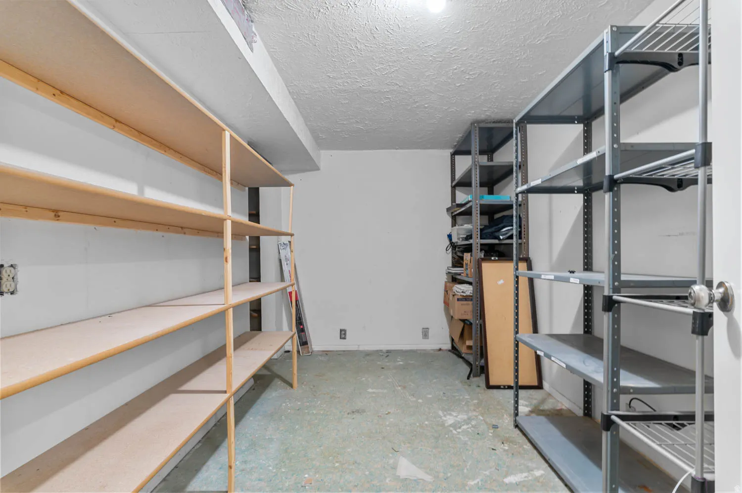 Utility room featuring extensive built-in shelving, durable concrete flooring, and overhead lighting