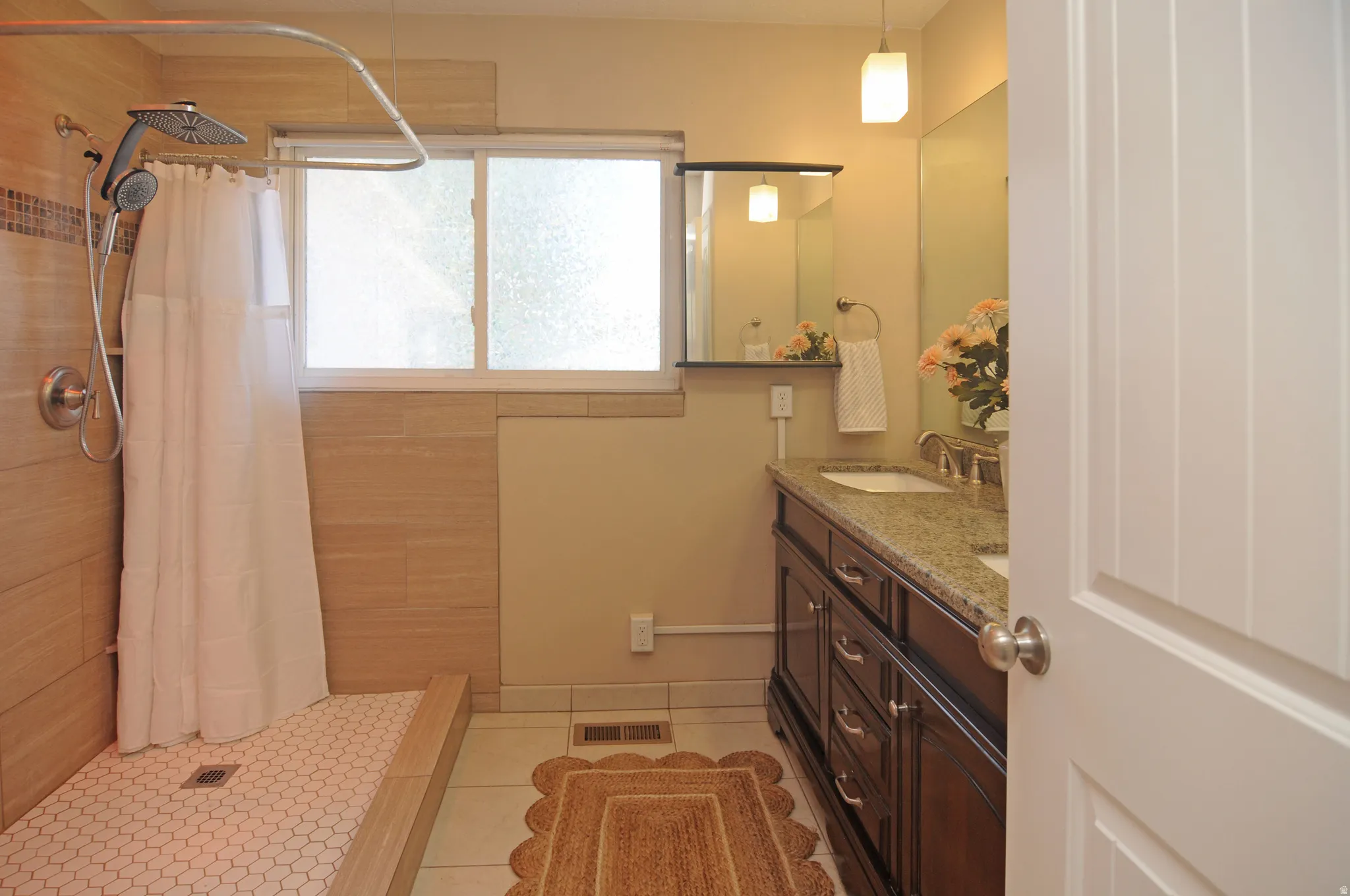 Walk-in shower with hexagonal tile flooring, a dual-head shower fixture, and a window