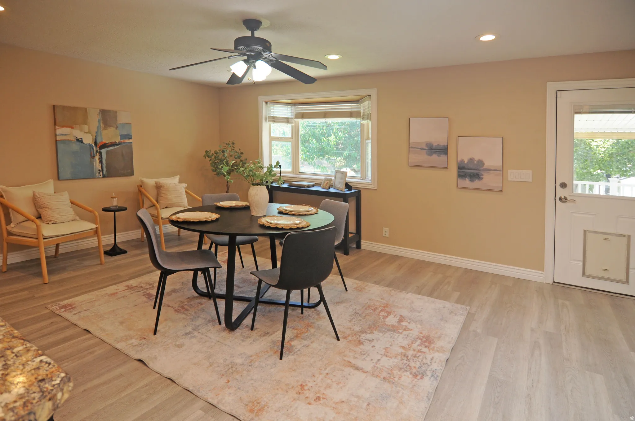 Recessed lighting, ceiling fan with light fixture, bay window, wood-finish flooring, and exterior door with glass insert