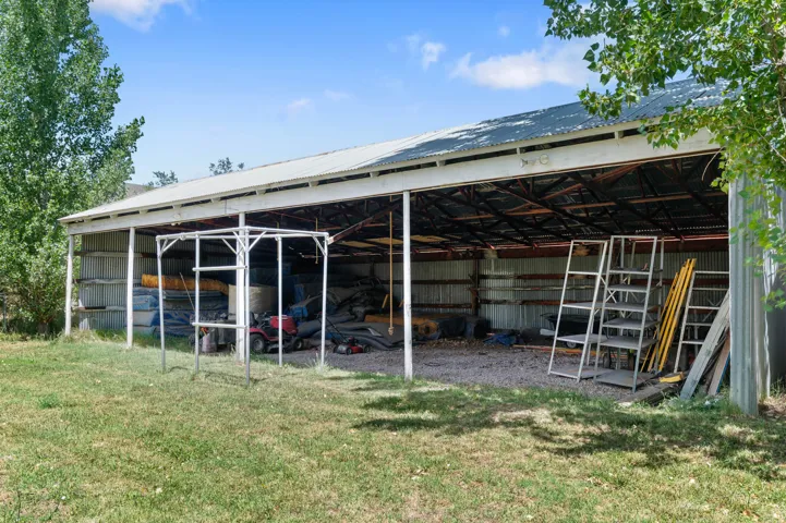 Expansive open-sided barn featuring a metal roof, exposed structural beams, and corrugated metal siding