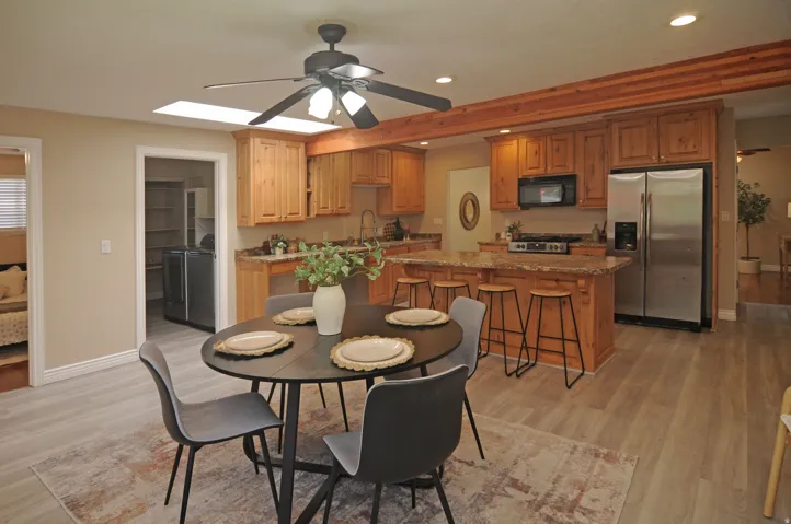 Spacious kitchen featuring wood cabinetry, stainless steel appliances, a center island with seating, and wood-finish flooring