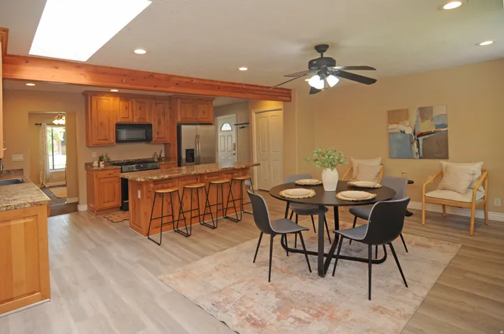 Kitchen with light wood cabinetry, granite-style countertops, stainless steel appliances, and a central island with bar seating