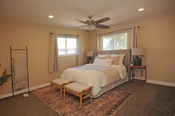 Recessed ceiling lighting, ceiling fan, two windows with curtain rods, and neutral wall tones