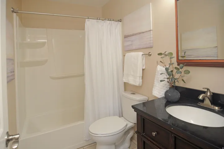 Bathroom featuring a dark wood-finish vanity, undermount sink, dark countertop, and brushed nickel faucet