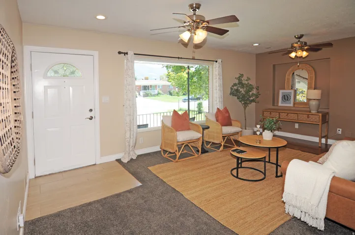 Recessed lighting, ceiling fans, front entry door with decorative glass insert, wood-finish flooring, and large window with exterior railing