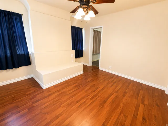 Room featuring wood-finish flooring, a built-in bench, and a ceiling fan with integrated lighting