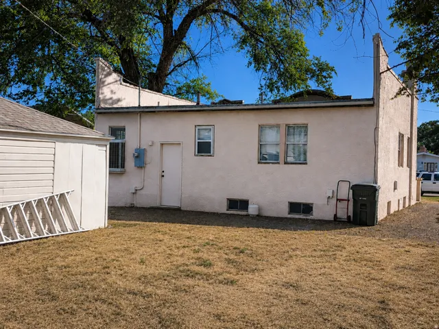 Stucco exterior with multiple windows, a flat roof, and a separate outbuilding featuring siding