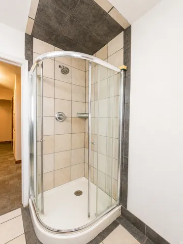 Enclosed shower stall featuring a curved glass door, white shower pan, and chrome fixtures
