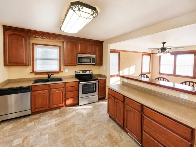 Kitchen with wood-finish cabinetry, stainless steel appliances, and a double-basin sink