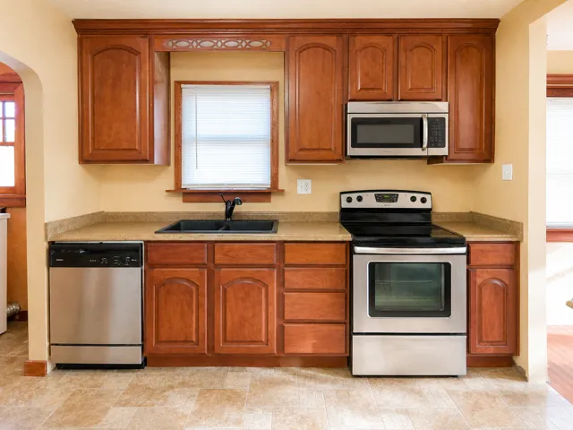 Kitchen featuring wood cabinetry, stainless steel appliances, a double basin sink, and laminate countertops
