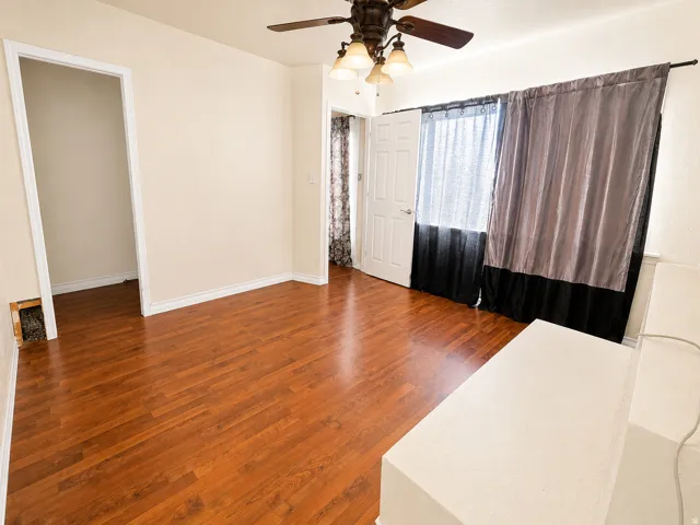 Spacious room featuring wood-finish flooring, light-toned walls, and white trim