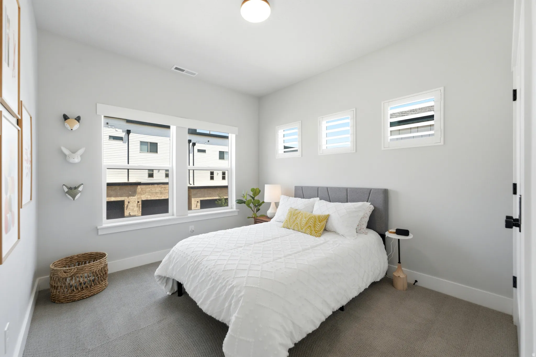 Bright room featuring gray carpeting, multiple windows with white trim, a recessed ceiling light fixture, and a white door with black hardware