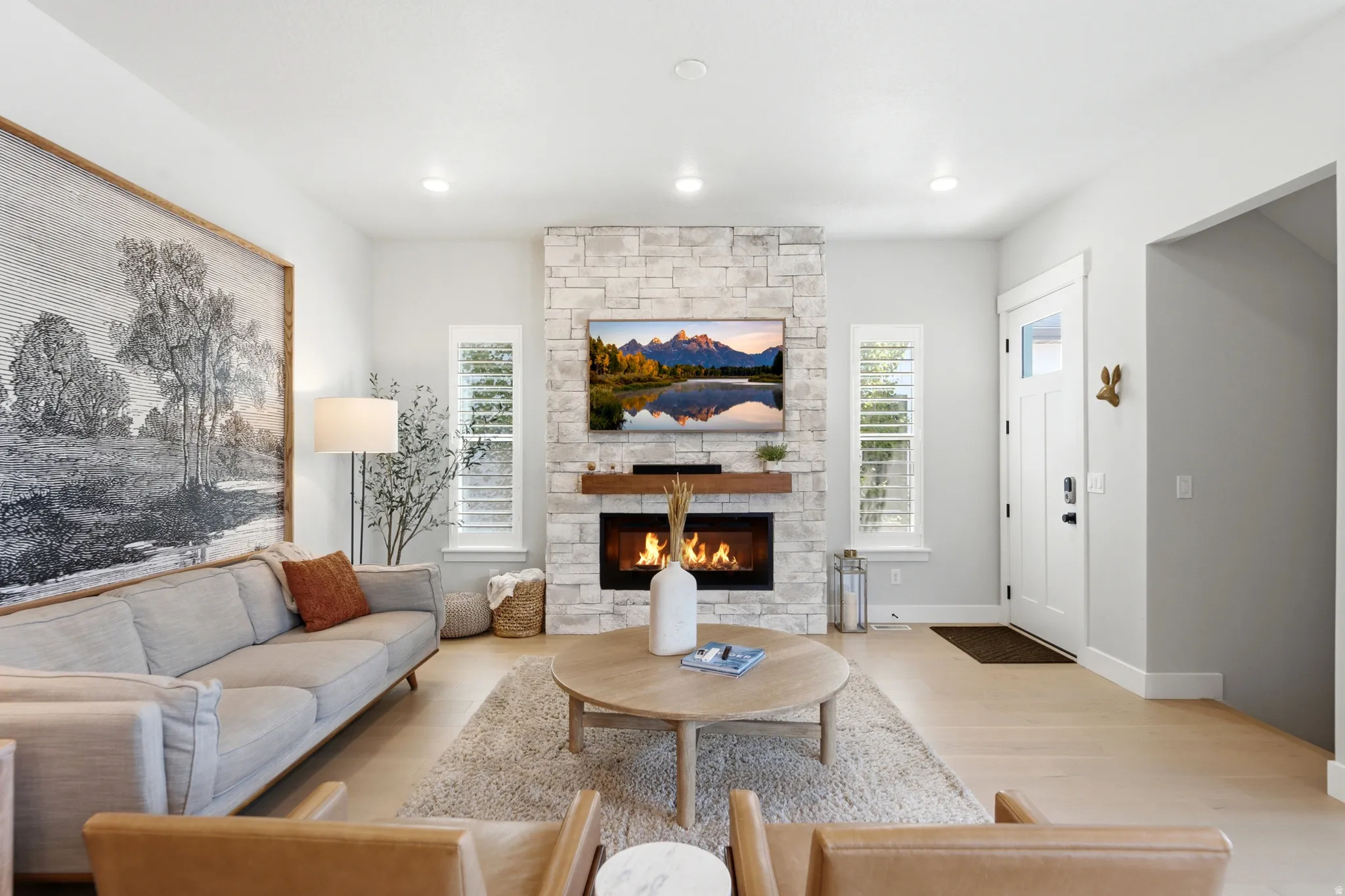 Living area with a stacked stone fireplace featuring a wood mantle