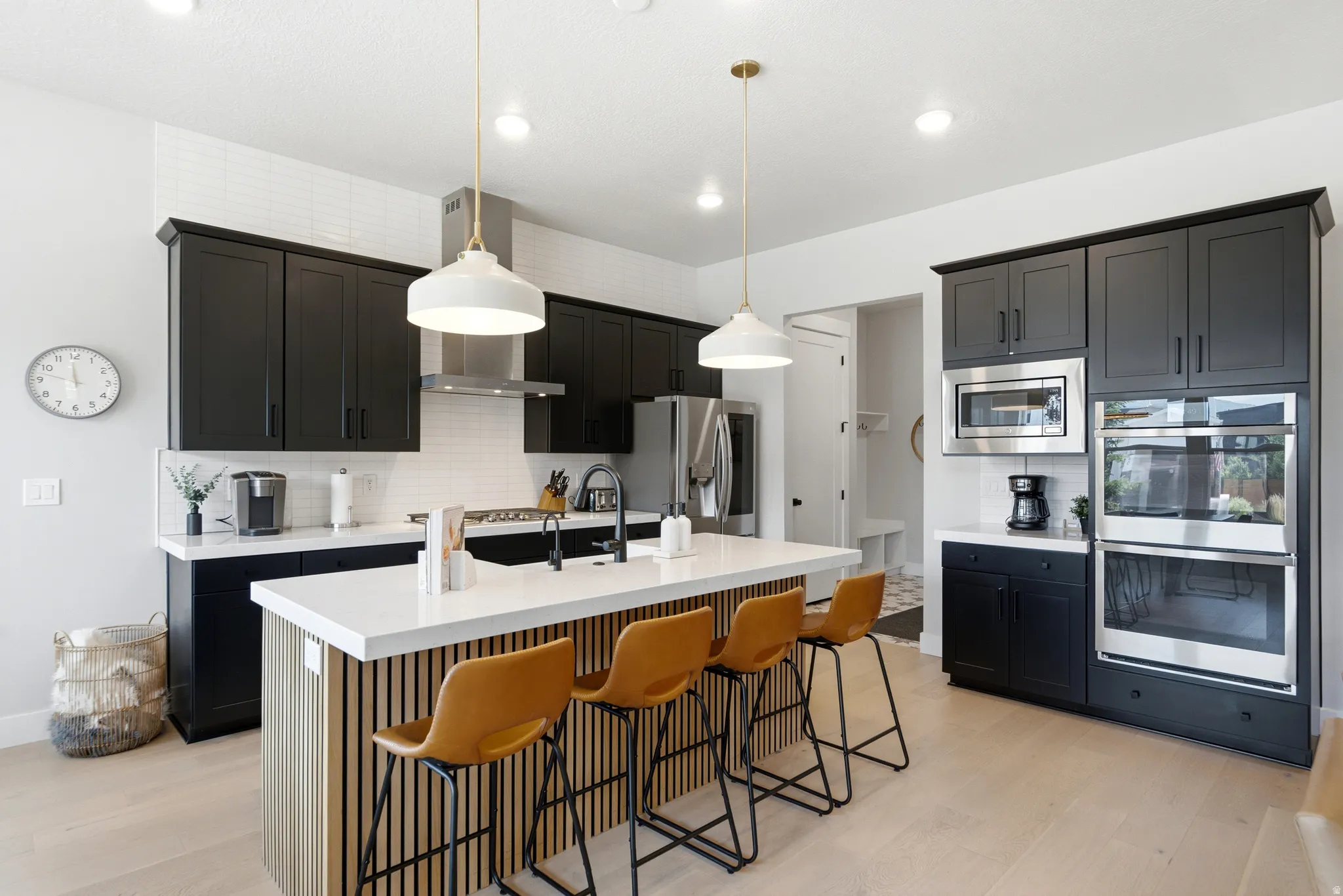 Modern kitchen featuring black cabinetry, a white subway tile backsplash, and light wood-finish flooring