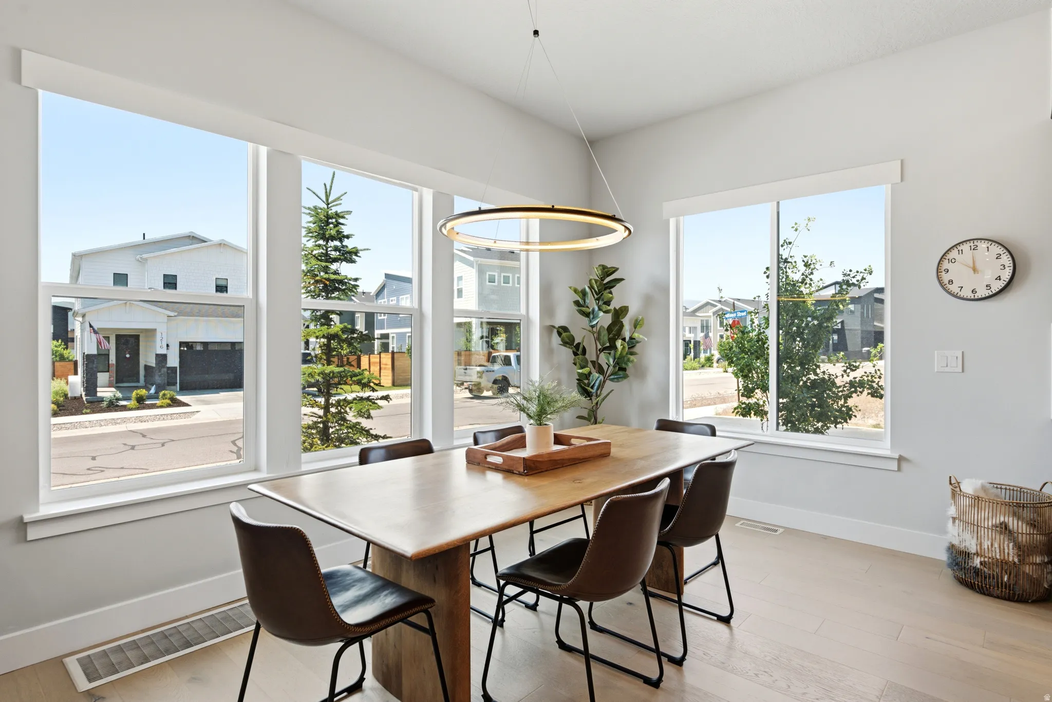 Open-concept dining area featuring light wood-finish flooring and a contemporary linear chandelier