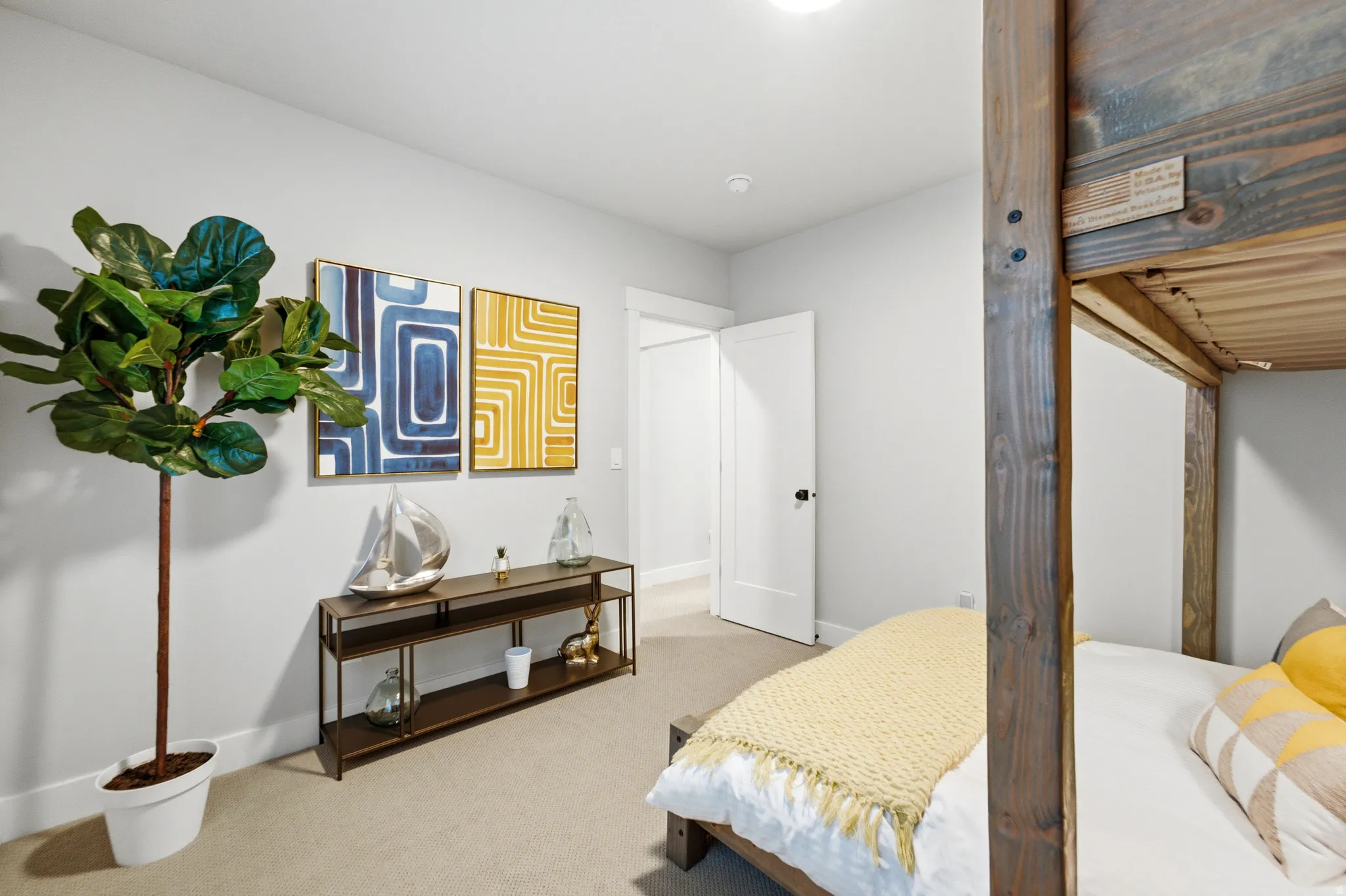 Carpeted room featuring a built-in wooden bunk bed frame, white walls, and a white door with a black handle