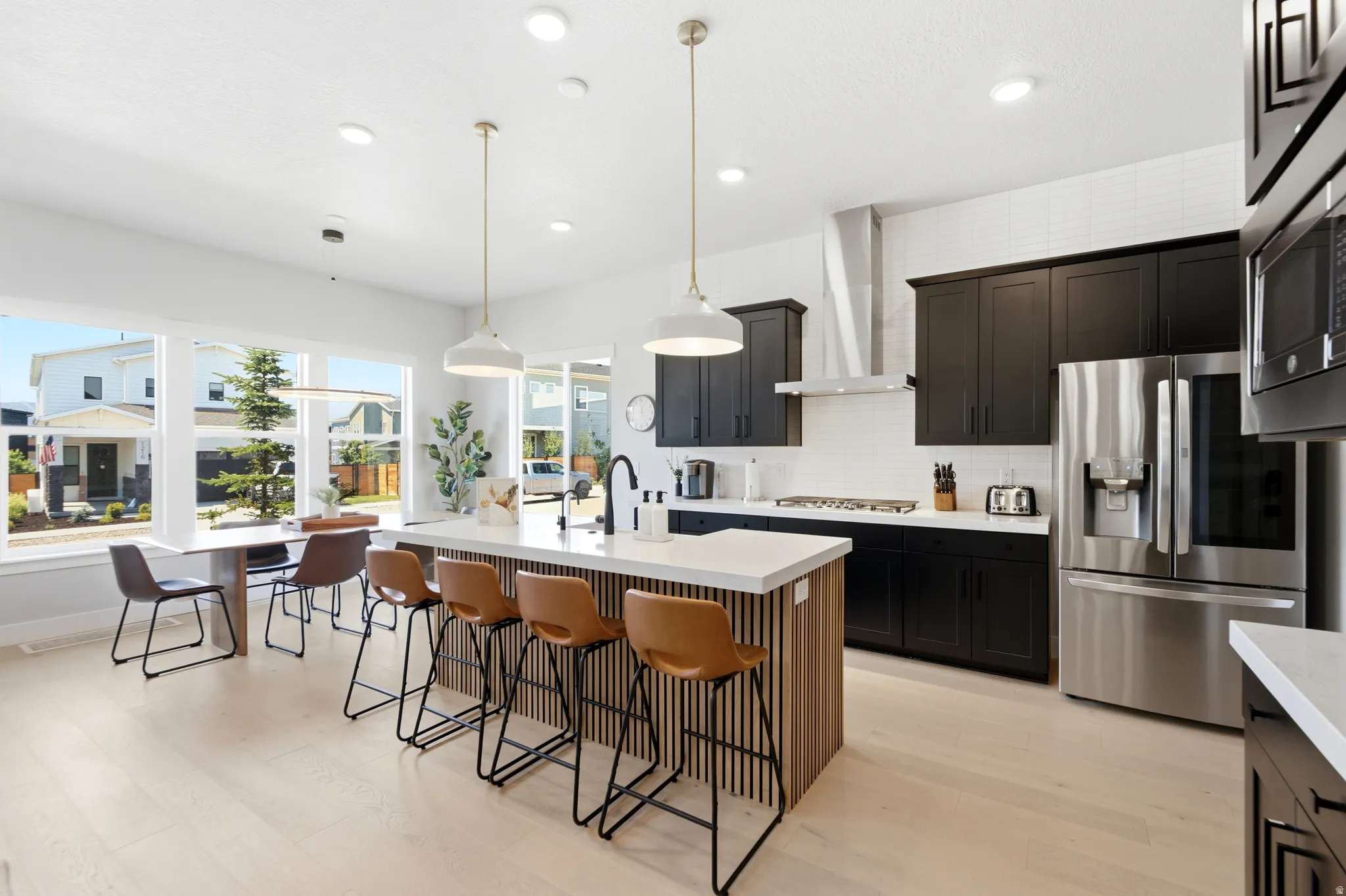 Open-concept kitchen featuring an oversized island with slat wood paneling, white countertops, and pendant lighting