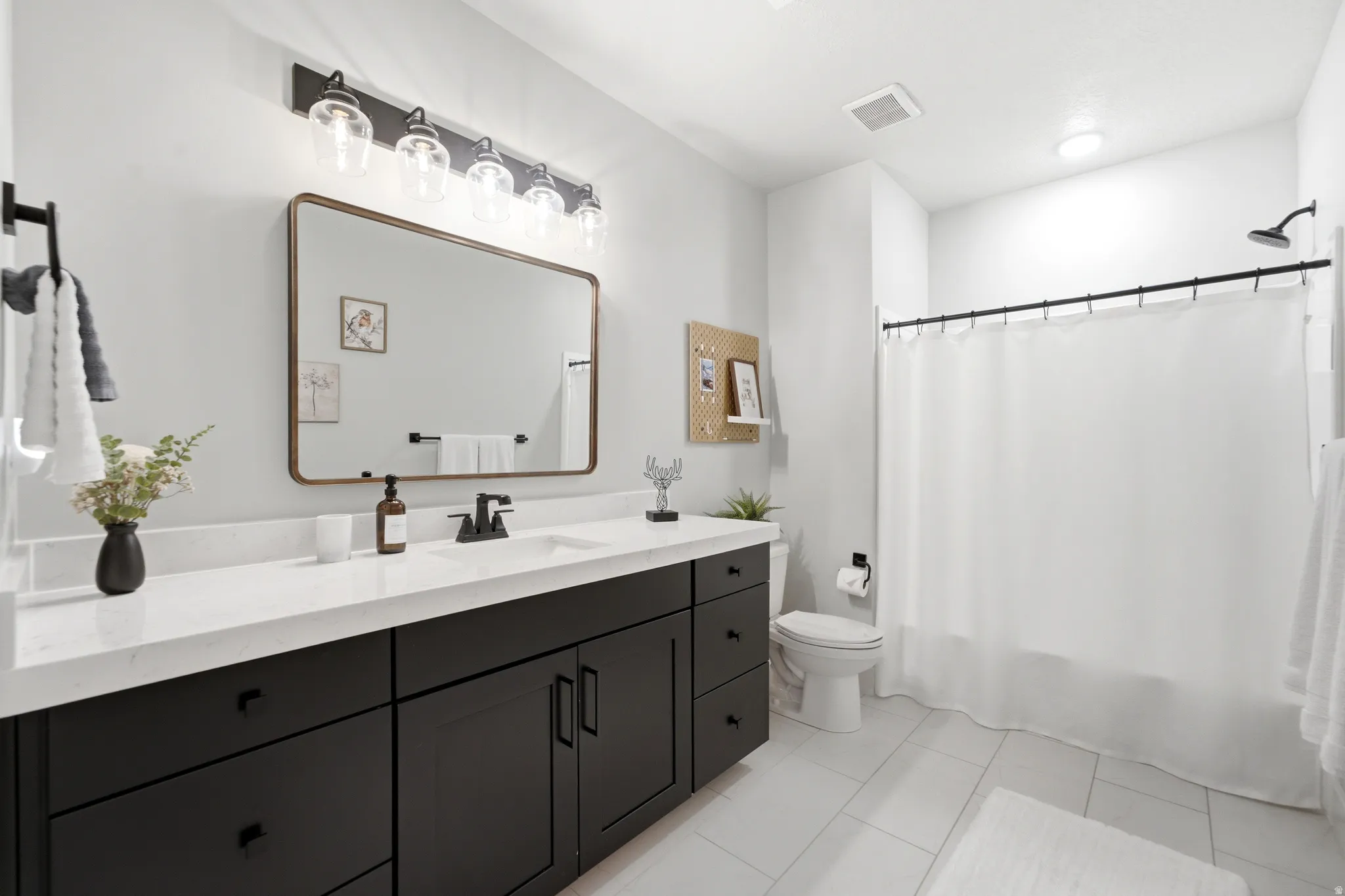 Bathroom featuring a dark wood-finish vanity with a white countertop, rectangular sink, and matte black faucet
