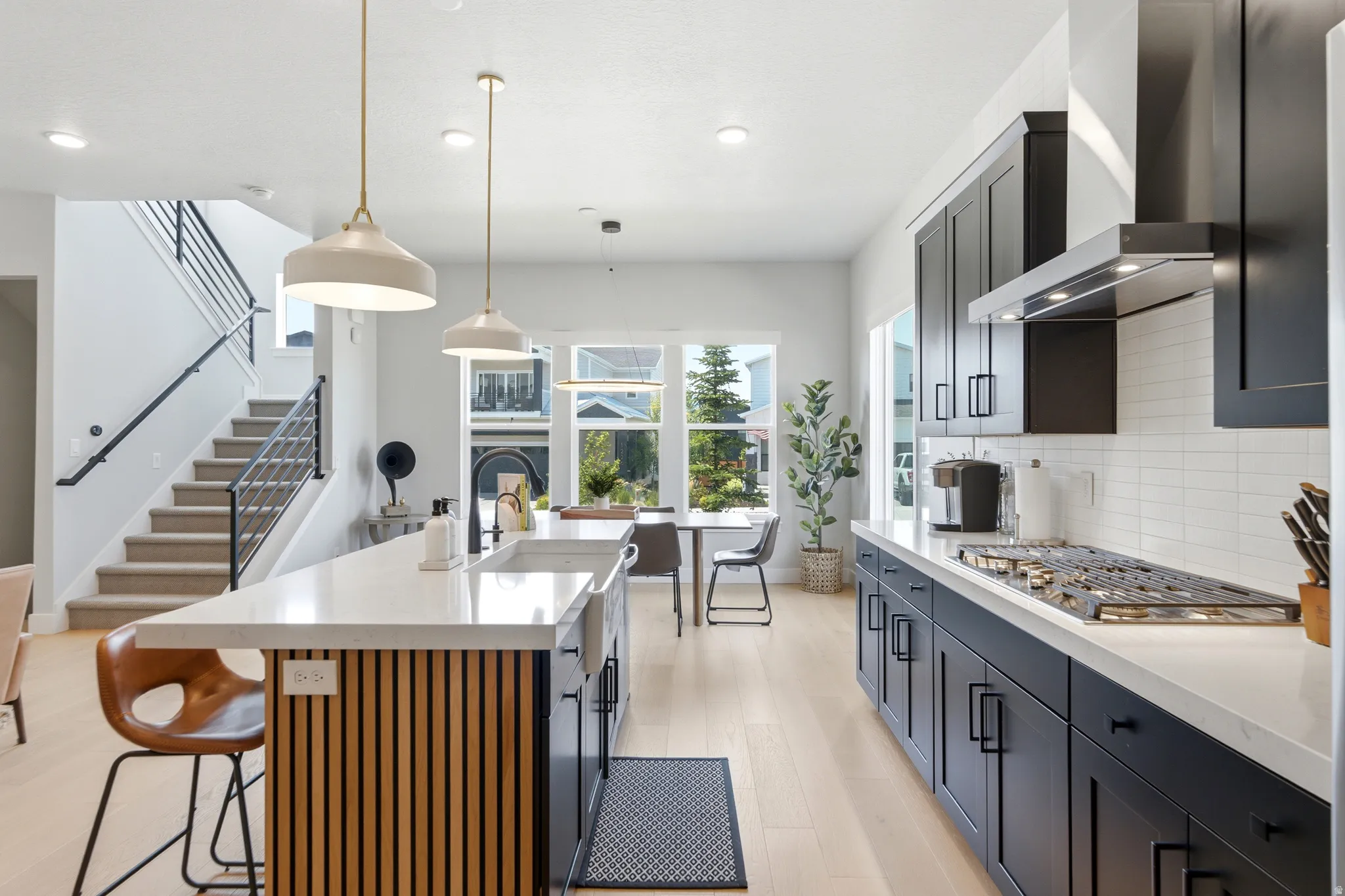 Modern kitchen featuring dark cabinetry, light countertops, and a subway tile backsplash