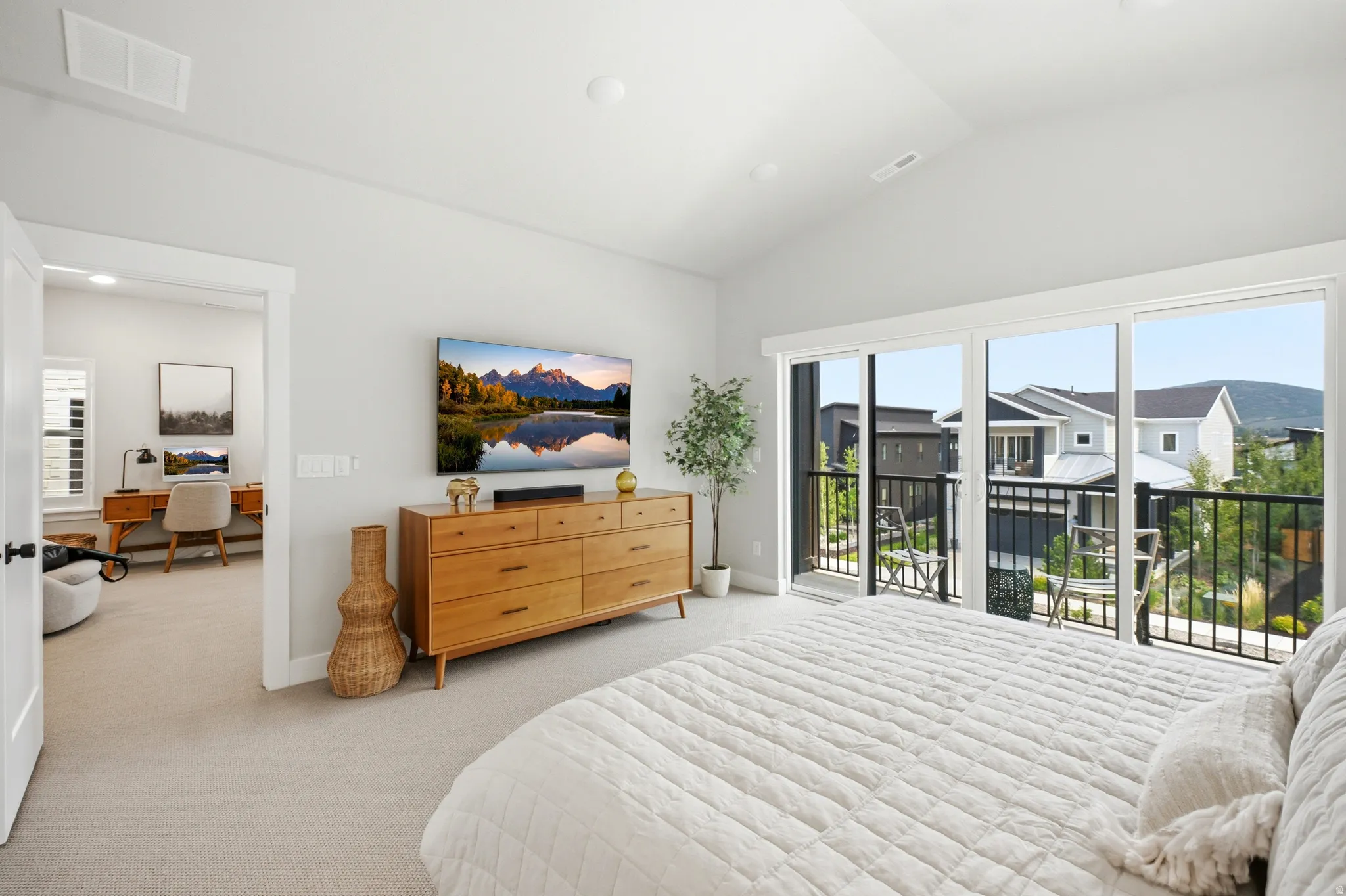 Bedroom featuring vaulted ceilings, light gray carpeting, and a full-light sliding glass door leading to a balcony