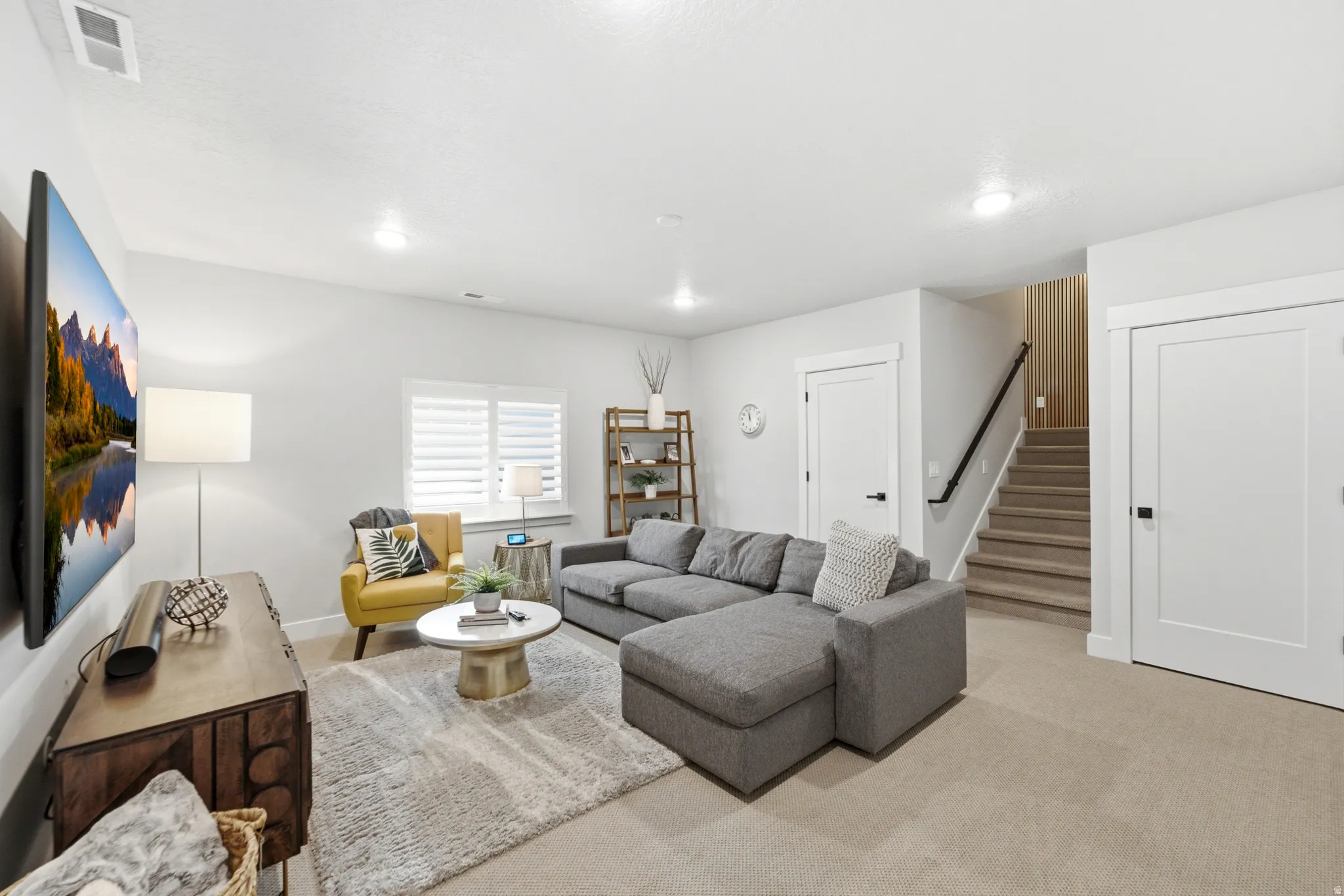 Light-toned walls and carpeting define this interior space, featuring a window with white plantation shutters