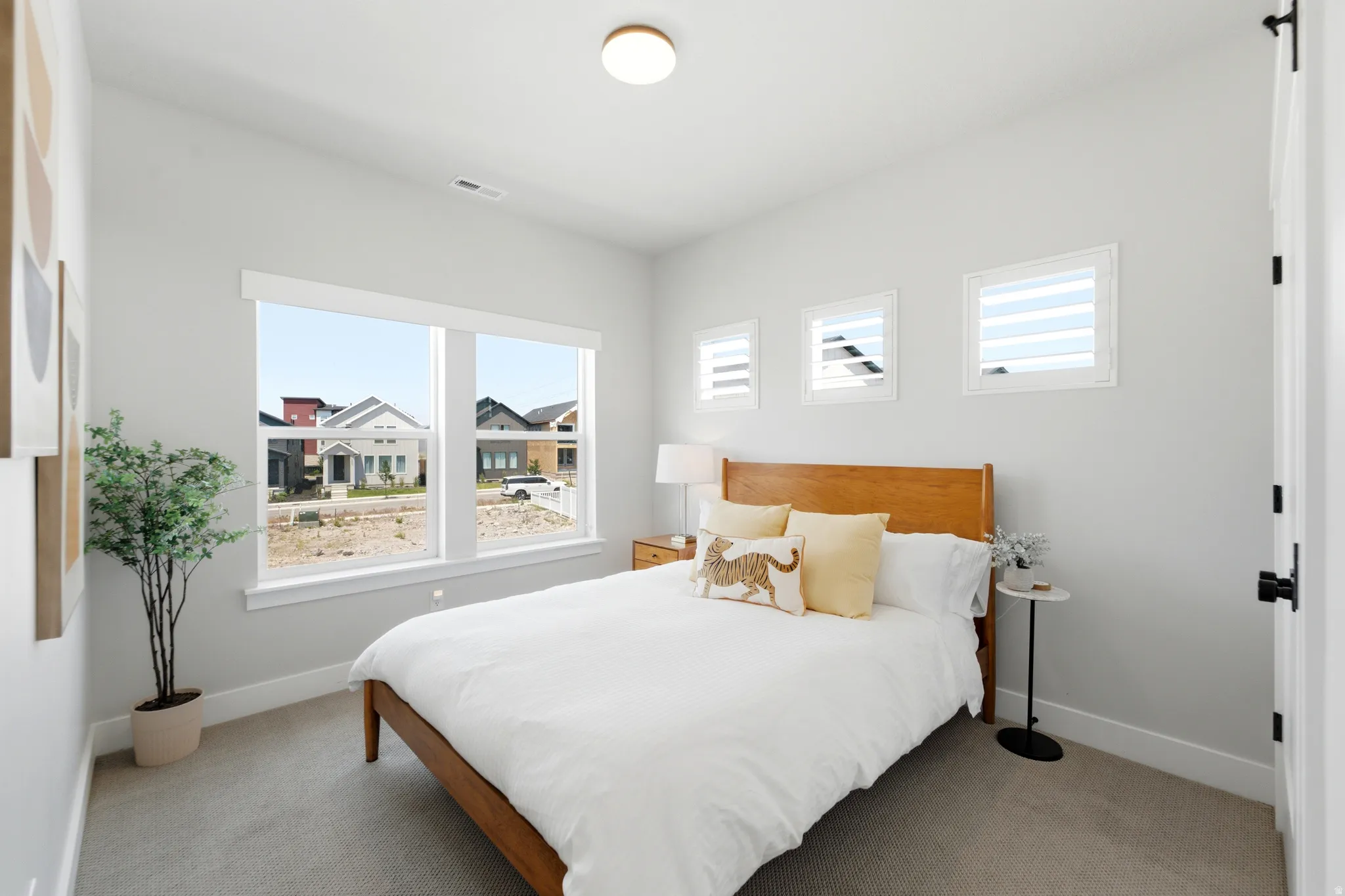Bedroom featuring light gray walls, carpet flooring, a large multi-pane window, and three smaller windows with white blinds