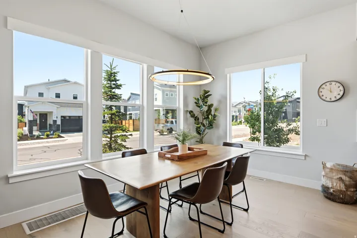 Open-concept dining area featuring light wood-finish flooring and a contemporary linear chandelier